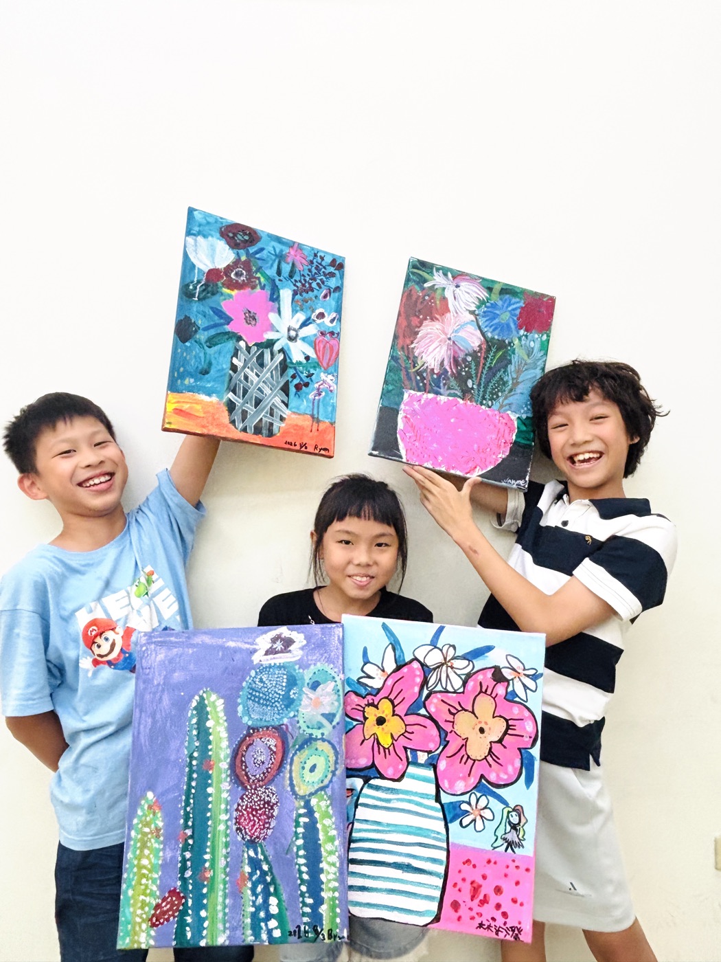 三位小小藝術家開心舉著自己的油畫作品